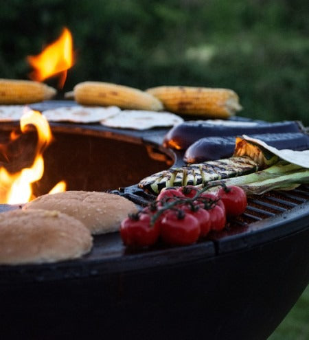 Castworks Hergóm Meteor low base outdoor fire pit complete set showing the fire bowl and surrounding base in a backyard setting.