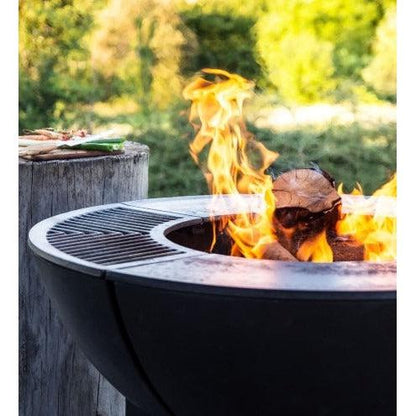 Castworks Hergóm Zenith high base outdoor fire pit complete set with fire bowl, stand, and accessories in a backyard setting.